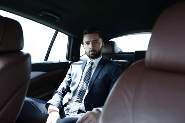 Exitoso hombre de negocios sentado en el asiento trasero de un coche — Foto de Stock