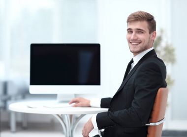 Masada oturan ve kameraya bakarak başarılı iş adamı.