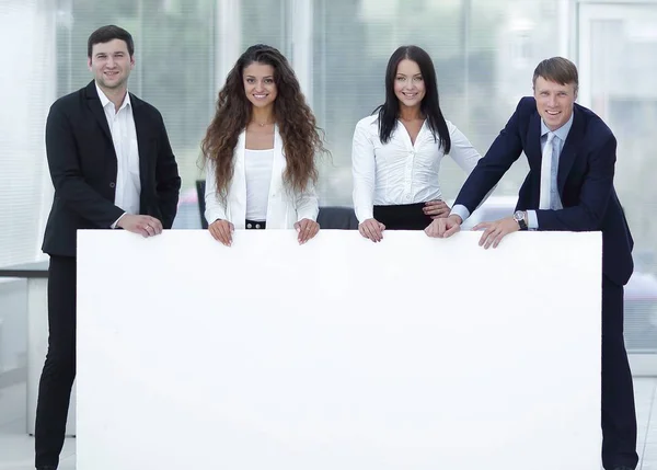 Equipo empresarial sosteniendo banner blanco en blanco —  Fotos de Stock