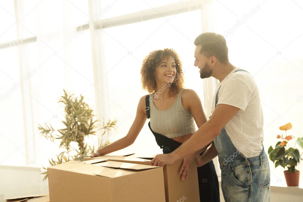 Newlyweds carry boxes in a new apartment.