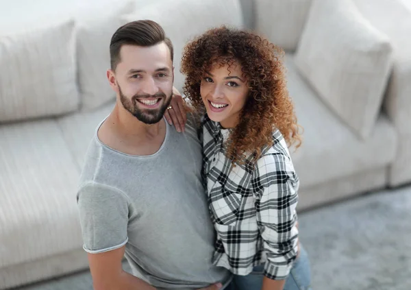 young couple standing in new living room and looking at camera