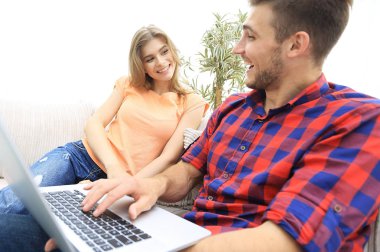 Mutlu modern çift internette sörf yapıyor ve evde dizüstü bilgisayarla çalışıyor.