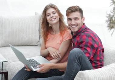 Dizüstü bilgisayarı olan iki öğrenci kanepede oturuyor.