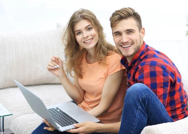 Par de estudantes com um laptop sentado no sofá — Fotografia de Stock