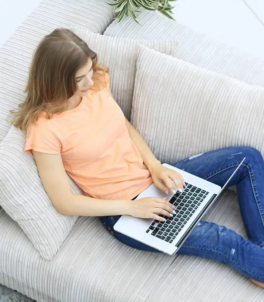 kız öğrenci dizüstü bilgisayar kanepede döşenmesi ile çalışma.