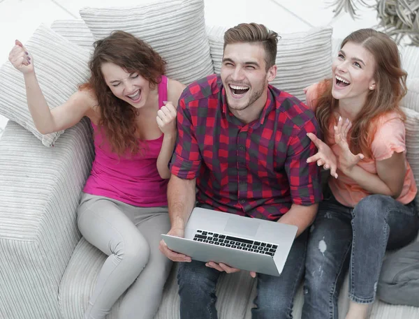 Gruppe von Freunden schaut sich ein Video auf einem Laptop an und lacht — Stockfoto