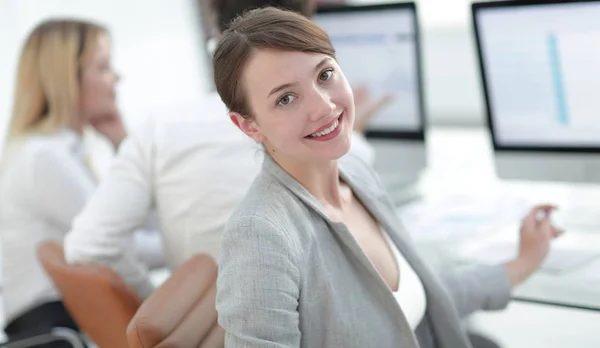 Rückansicht. schöne Geschäftsfrau am Schreibtisch sitzend und in die Kamera blickend. — Stockfoto