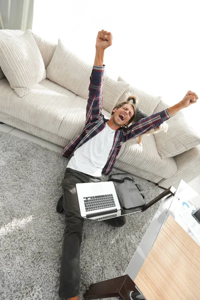 Happy guy with laptop jubilant in spacious living room. — Stock Photo, Image