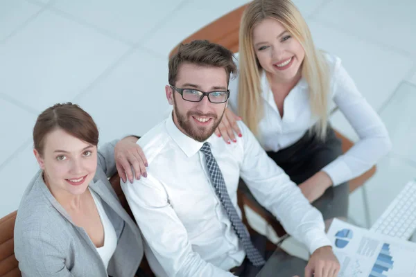 Equipe de negócios bem sucedida sentado à mesa e olhando para a câmera . — Fotografia de Stock