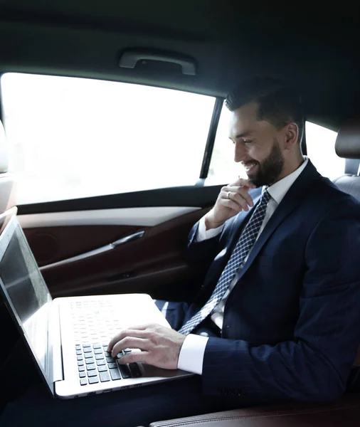 Επιχειρηματίας, πληκτρολογώντας κείμενο σε φορητό υπολογιστή, ενώ κάθεται στο αυτοκίνητο — Φωτογραφία Αρχείου