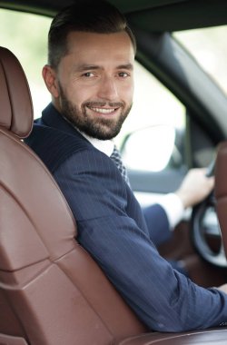 Kameraya bakarak bir arabanın ön koltuğunda otururken yakışıklı genç