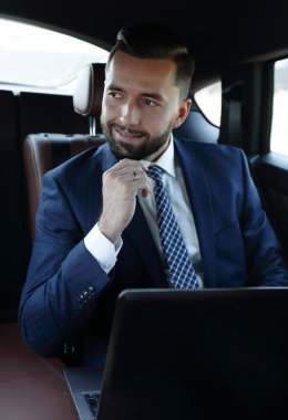 Bir arabanın arka koltuğunda oturan başarılı adam