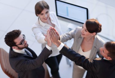 Başarılı bir iş ekibi ofiste birbirlerine beşlik çakıyor.