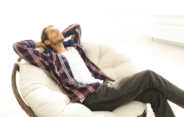 Sério cara descansa sentado e sonhando em uma grande cadeira confortável . — Fotografia de Stock