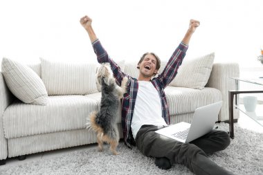mutlu genç adam köpeğiyle oturma odasında exults