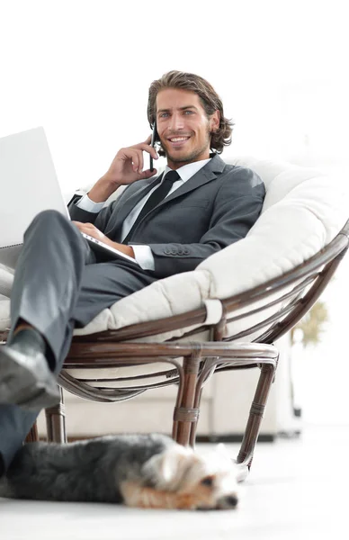 Onun evinde sandalyede oturan smartphone cep telefonu ile konuşurken işadamı — Stok fotoğraf