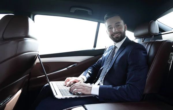 Young businesswoman working on her laptop while sitting in the car — Stock Photo, Image