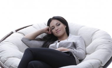 Genç bir kadın rahat, yumuşak, büyük bir koltukta oturuyor.