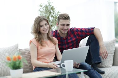 Genç çift çalisarak koltukta oturan laptop