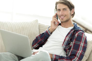 cep telefonu üzerinde konuşurken laptop ile ciddi genç adam