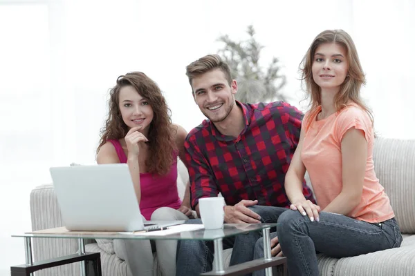Group of students sitting on a couch behind a coffee table. — Stock Photo, Image
