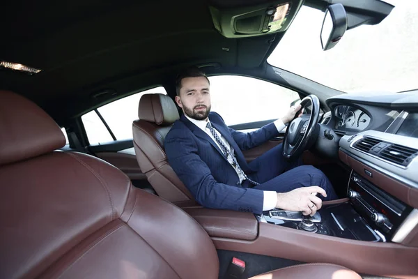 Nézd meg benne, üzletember ül a volánnál, az autó oldalról — Stock Fotó