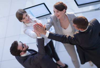 Başarılı bir iş ekibi ofiste birbirlerine beşlik çakıyor.