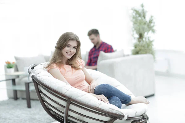 Beautiful young woman sitting in a large comfortable chair — Stock Photo, Image