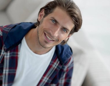 dizüstü bilgisayarda çalışan ve kameraya bakarak bir genç adam. Yukarıdan görüntülemek