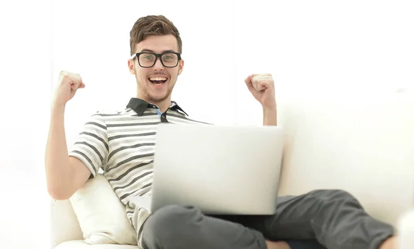 Lycklig man med laptop sitter i soffan — Stockfoto
