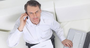sandalyede oturan ve bir smartphon üzerinde konuşurken işadamı
