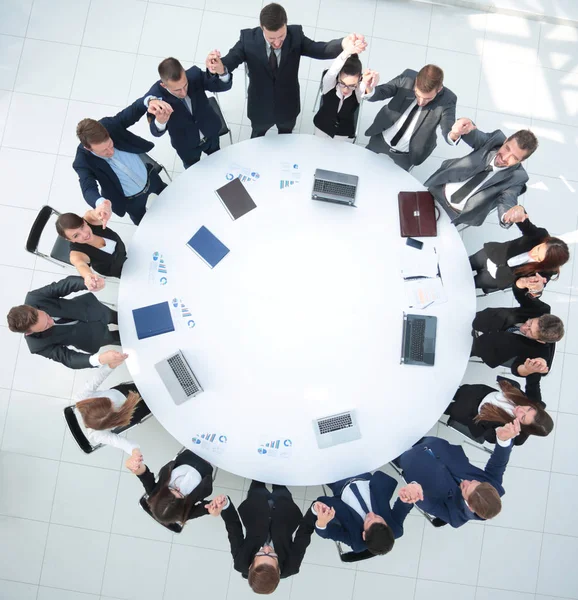 一个庞大的商业团队坐在圆桌前，举起双手 — 图库照片