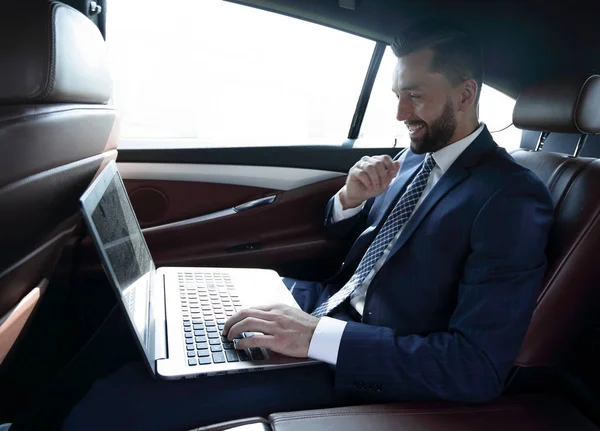 ビジネスマンの車に坐っている間のラップトップ上のテキストを入力します。 — ストック写真