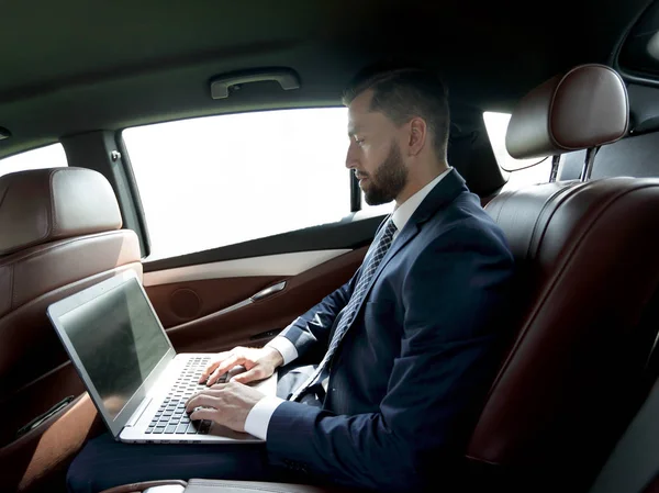 Podnikatel na přenosném počítači v sedadle automobilu — Stock fotografie
