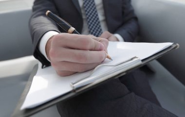 İşadamı bir sözleşme imzalar. Elinde kalem tutan.