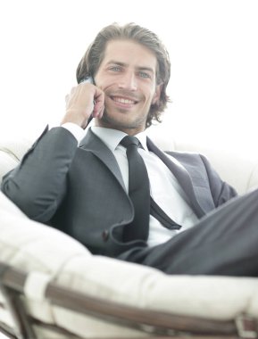 iş adamı rahat bir sandalyede otururken Smartphone'da konuşuyor.