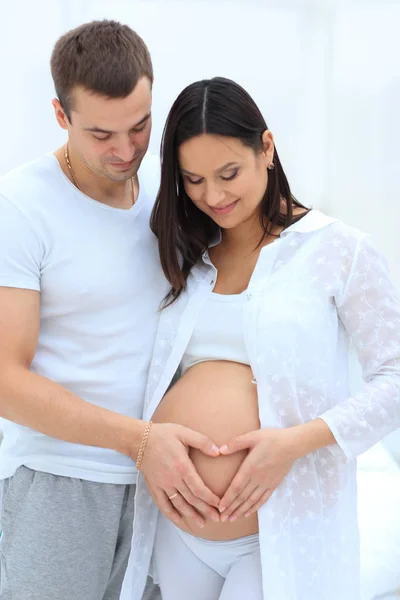 Муж и беременная жена со сложенными руками в форме сердца на животе — стоковое фото