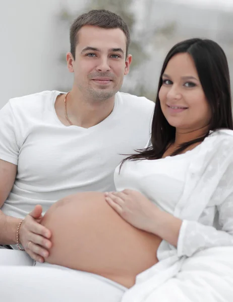 Retrato de mulher grávida com o marido sentado no sofá — Fotografia de Stock