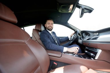 Yan emin işadamı görünümünden bir araba direksiyon başında oturur