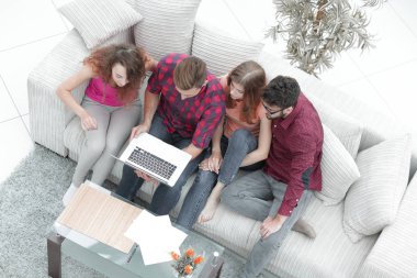 kanepede oturan dizüstü bilgisayar ile arkadaş grubu.