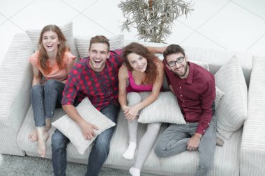 Neşeli bir arkadaş grubu kanepede oturup gülüyor..