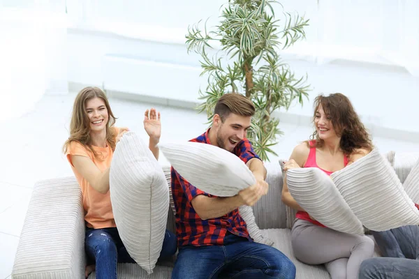Gruppe von Freunden spielt Kissenschlacht, sitzt auf der Couch — Stockfoto