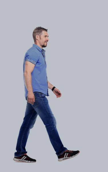 笑みを浮かべて若いカジュアルな男、白い背景の上を歩いての側面図 — ストック写真