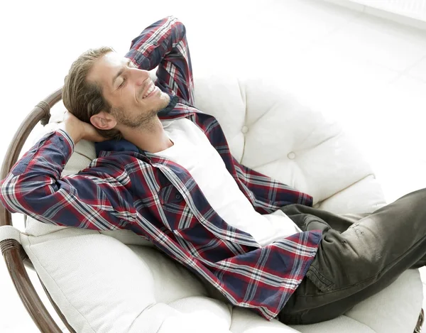 Modern adam büyük bir rahat sandalyede oturuyor dinleniyor. yan görünüm.