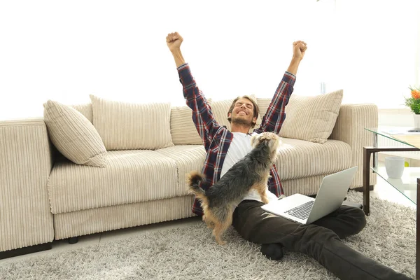 Glad kille med sin hund som sitter i ett rymligt vardagsrum — Stockfoto