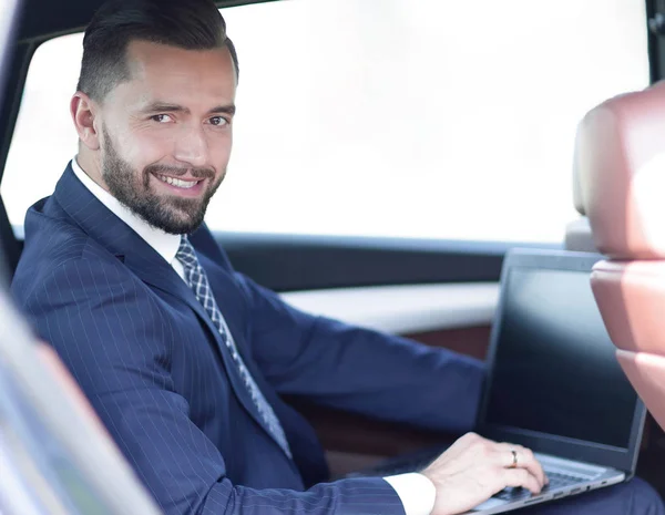 Primo piano di un uomo d'affari con un portatile seduto in macchina — Foto Stock