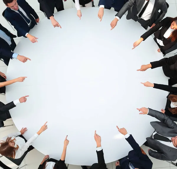 Close up .business team pointing in the center of the table . — стоковое фото