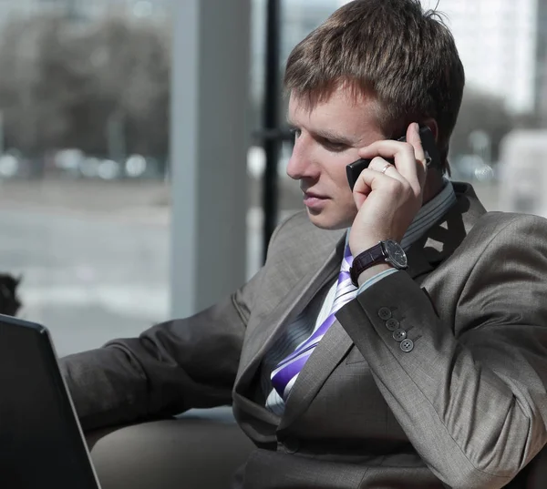 Aantrekkelijke Europese man praten over de telefoon terwijl het gebruiken van laptop. — Stockfoto