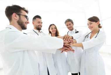 Doktorlar ve hemşireler tıbbi bir ekipte el ele tutuşuyorlar.