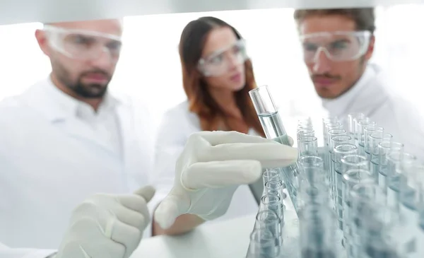 Bakgrundsbilden är en grupp av forskare som studerar vätskan i glasröret. — Stockfoto